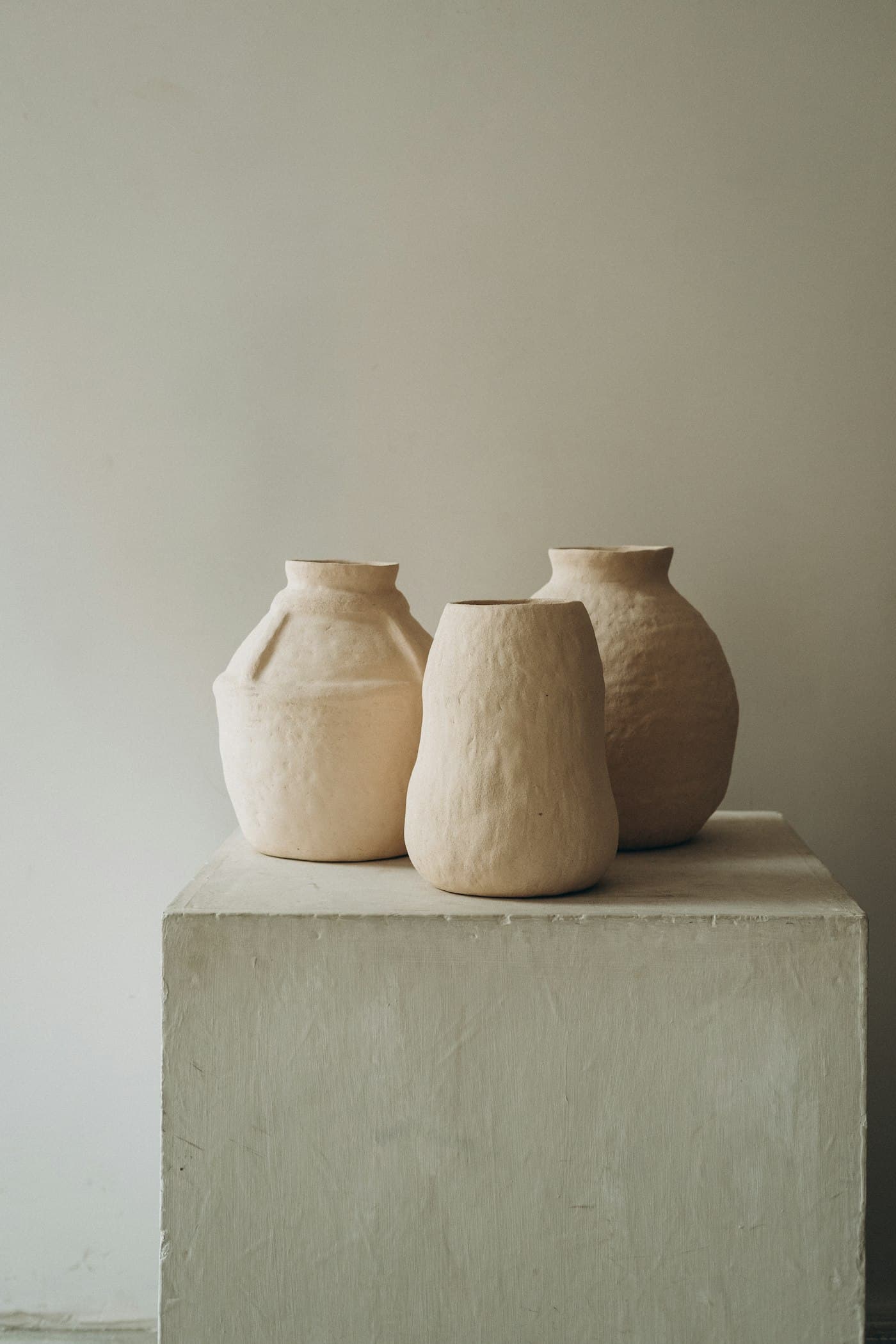 Trois vases en céramique brute posés sur un socle