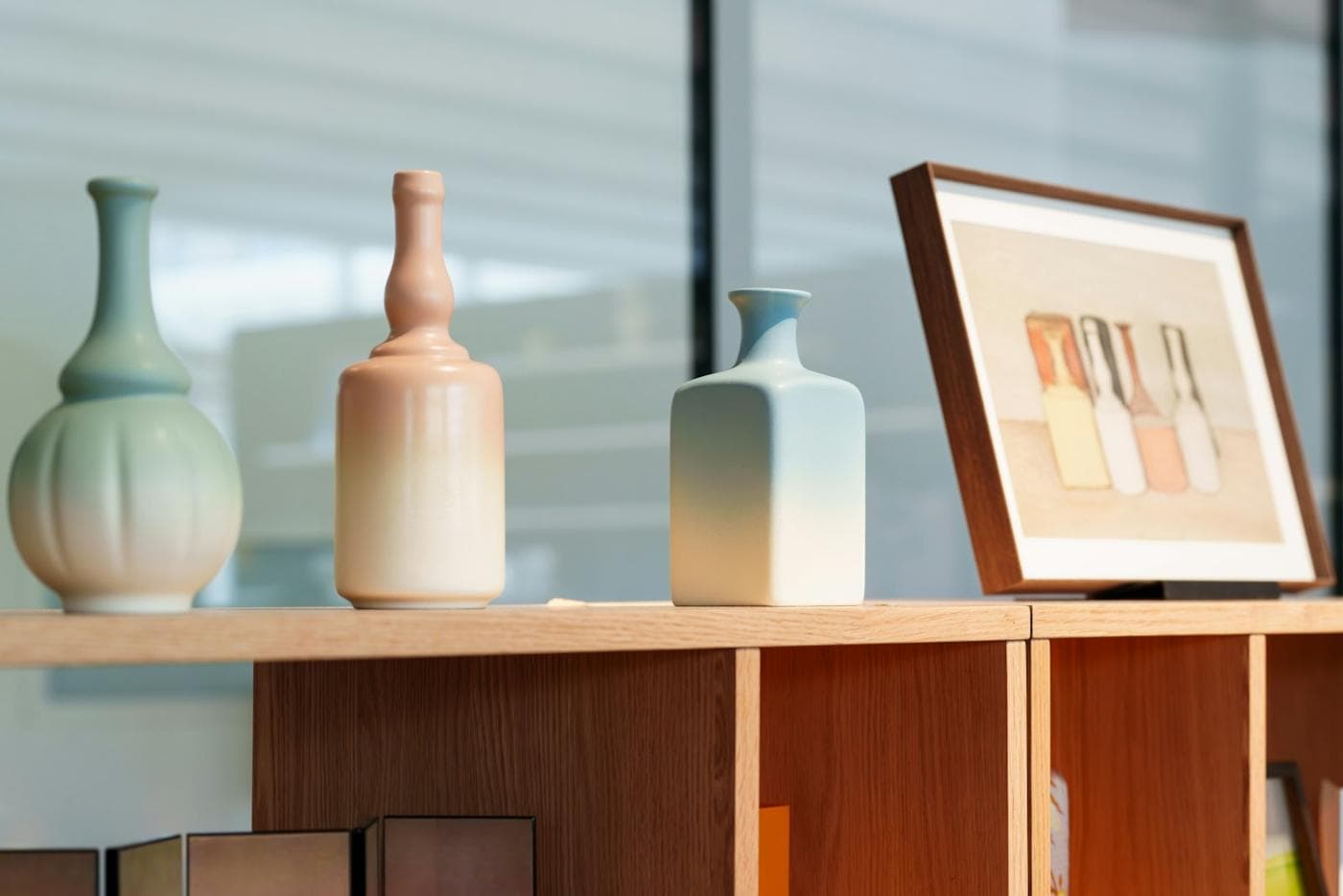 Vases en céramique et cadre posés sur une étagère en bois